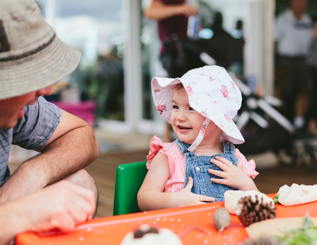 A baby girl smiling looking towards her father