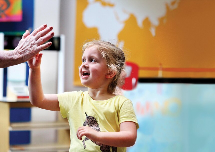 A young girl giving someone a high five happily