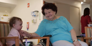 A grandmother admiring her baby grandchild smiling