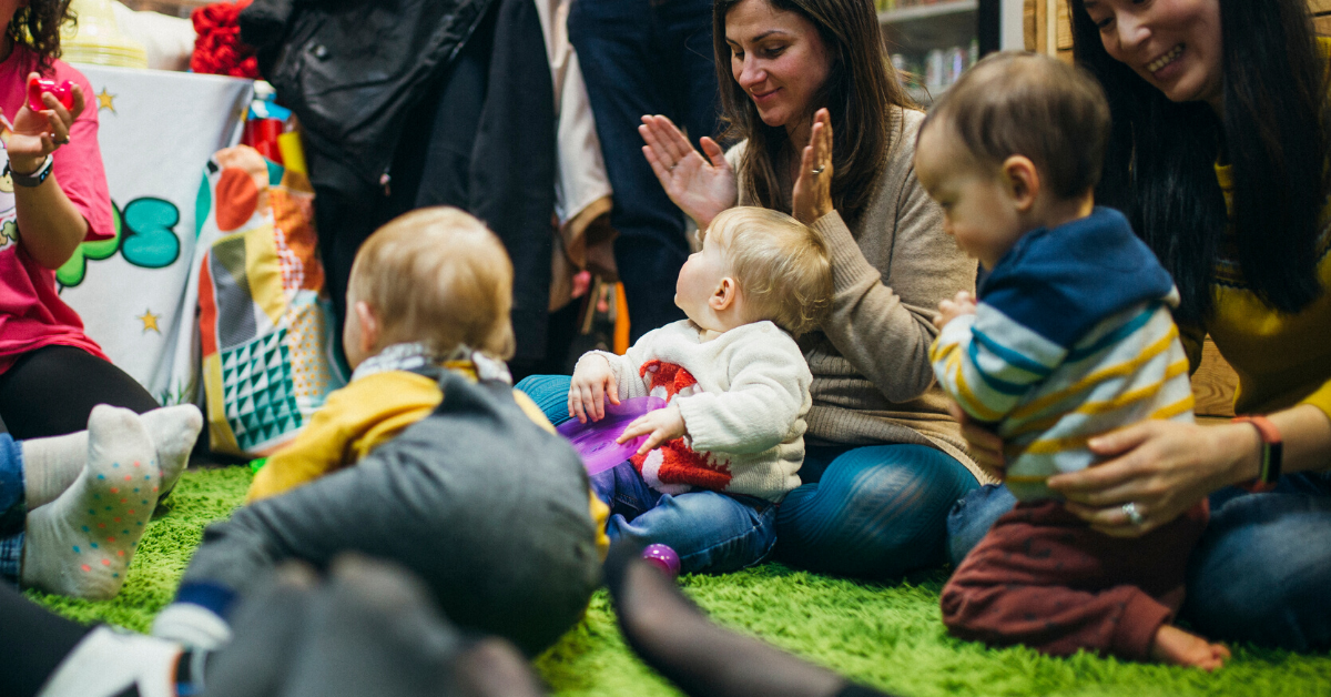 A group of mums with their babies sitting in a circle playing
