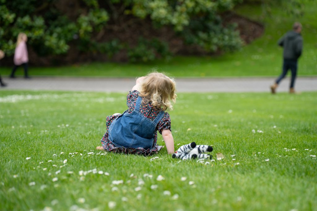 family with a toddler and children walking in nature exploring and learning, hiking in the trees and gardens. self playing