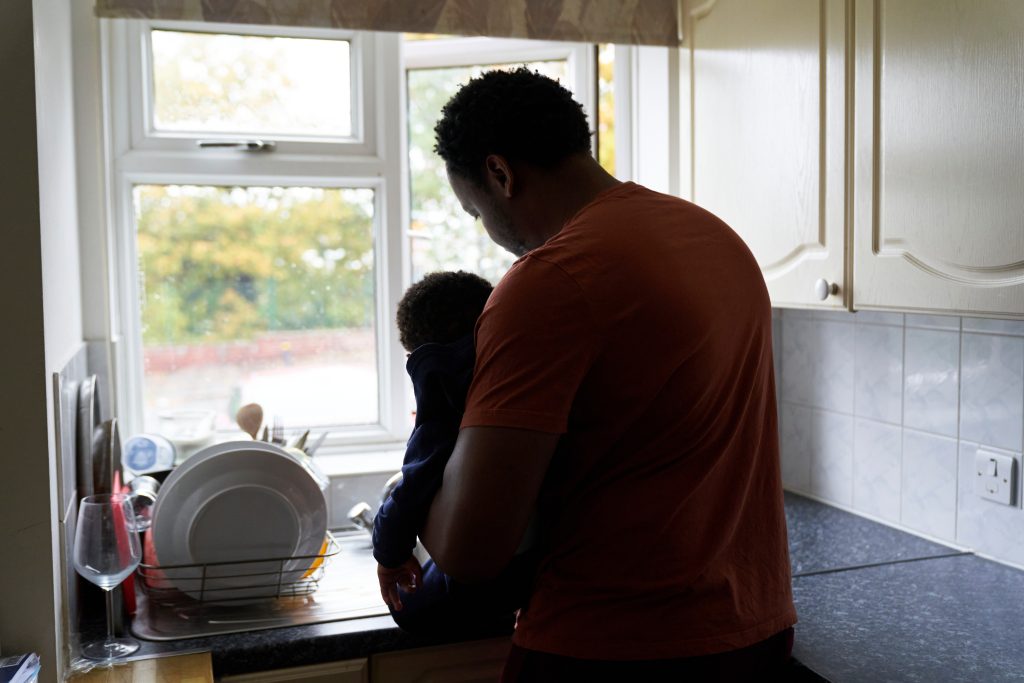 Busy father washing dishes whilst holding his baby