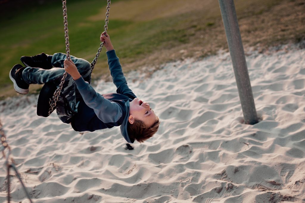 A child swinging upside down on a swing set