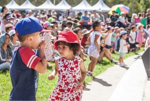 Children at an event engaged with crowds sitting behind them