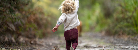 A child happily walking down a bush path