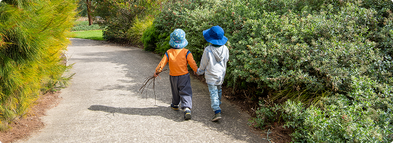 Two children walking away from the camera holding hands