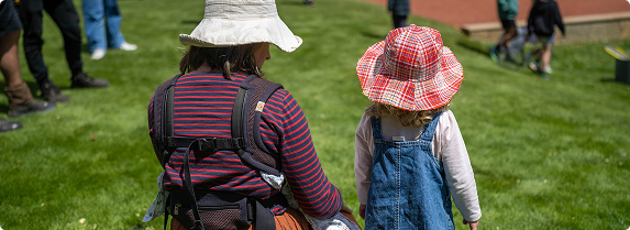 A mother and her daughter facing away from the camera wearing hats
